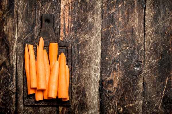 fresh peeled carrots on a cutting board on the old wooden table - Морковь тушёная постная