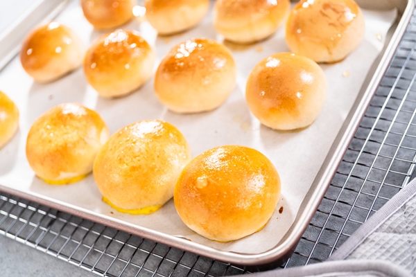freshly baked dinner rolls with an egg wash on a baking sheet lined with parchment paper - Булки постные