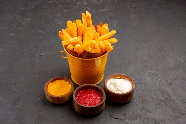 front view delicious french fries with ketchup mustard and mayyonaise on a dark space - Картофель, жареный во фритюре