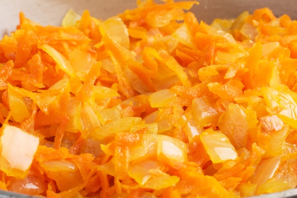 fry grated carrots and chopped onions with oil in a frying pan gray concrete - Гречневая каша с овощами