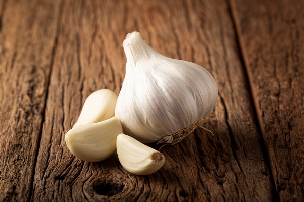 garlic bulb and garlic cloves on the wooden table - Картофельные ломтики с грибами