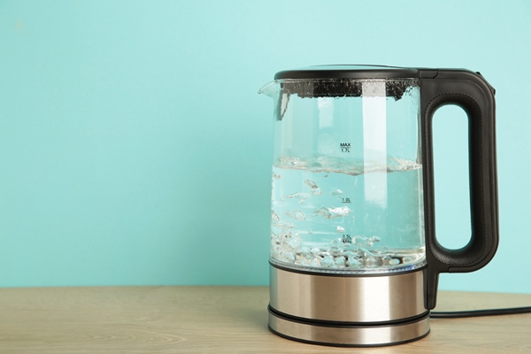 glass electric kettle with boiling water on blue background - Апельсиновый чай