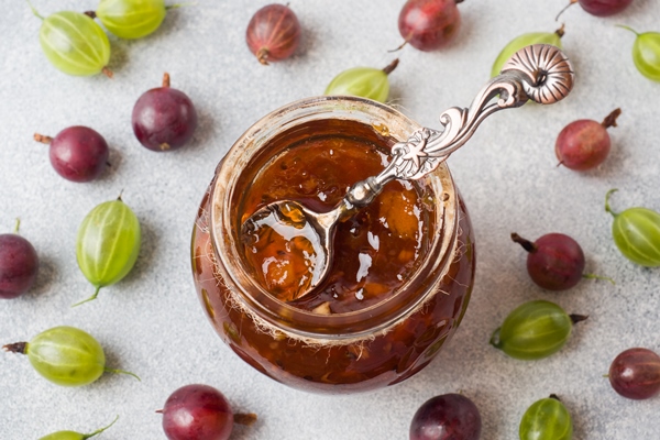 gooseberry jam in a jar with fresh gooseberry berries on a gray surface - Пудинг из риса со свежими фруктами