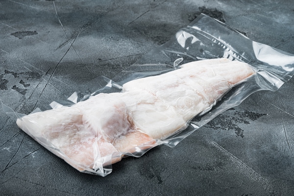 haddock white fish fillet in plastic market package on gray background with copy space for - Постные рыбно-овощные котлеты