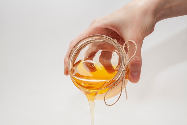 hand pouring honey from a jar 1 - Напиток клюквенный с мёдом