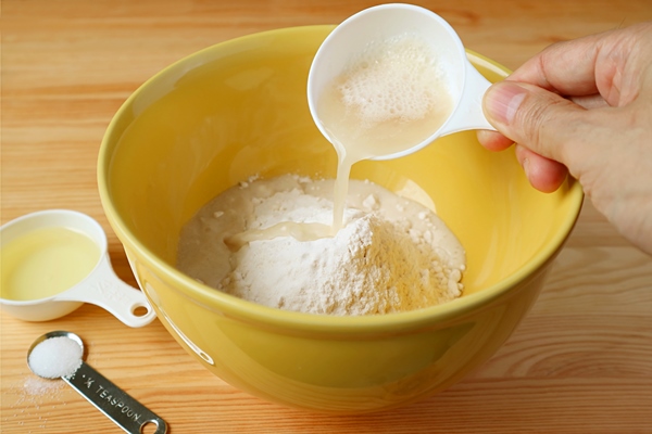 hand pouring yeast with water into the bowl of wholemeal flour - Штрудели с маком