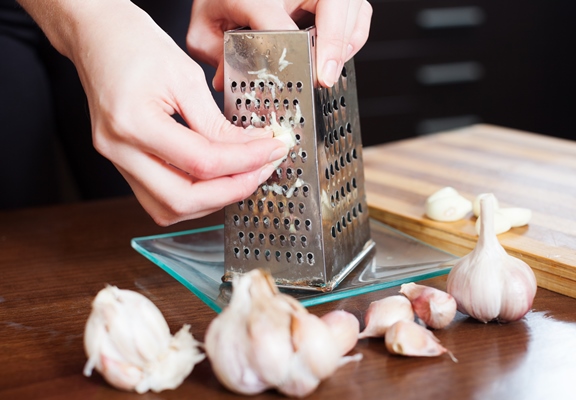 hands grating garlic with grater - Грузинский салат (без масла)