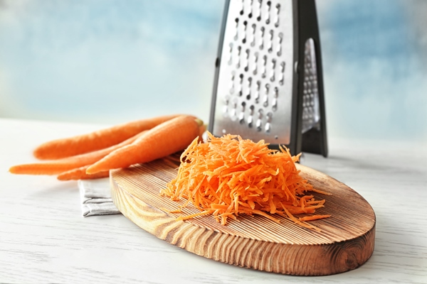 heap of grated carrot on wooden board - Морковный салат с сыром и чесноком