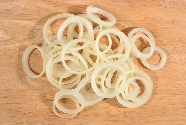 heap of onion slices on a wooden background - Салат луковый