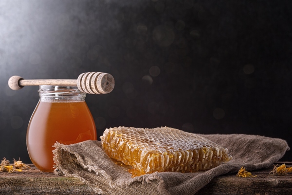 honey background sweet honey in the comb glass jar and a spoon for honey on the table dark background - Постное тесто на дрожжах для пирожков и пирогов