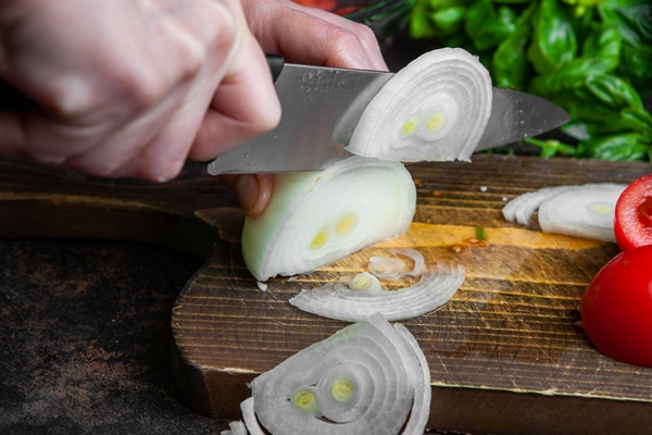 housewife cutting onion for salad on wooden board close up - Постный суп из консервов