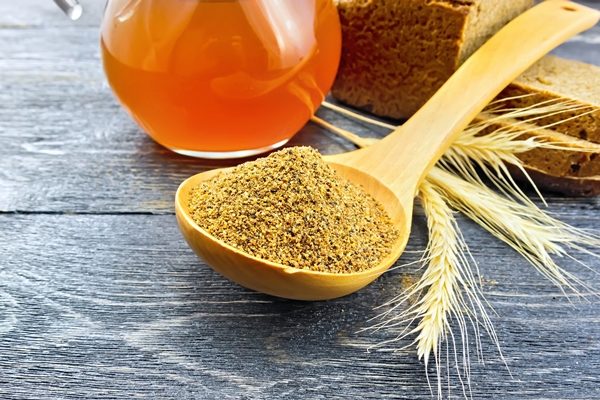 malt in a spoon bread kvass in a jug and spikelets on the background of wooden board - Квас хлебный белый