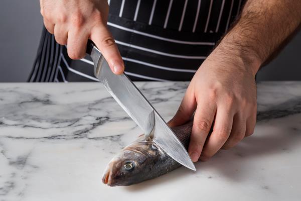 man cutting a bass fish for cooking - Окуни жареные, постный стол