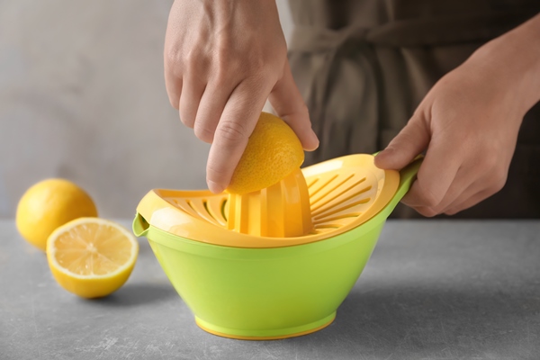 man extracting lemon juice with plastic squeezer - Фруктовый салат, постный стол