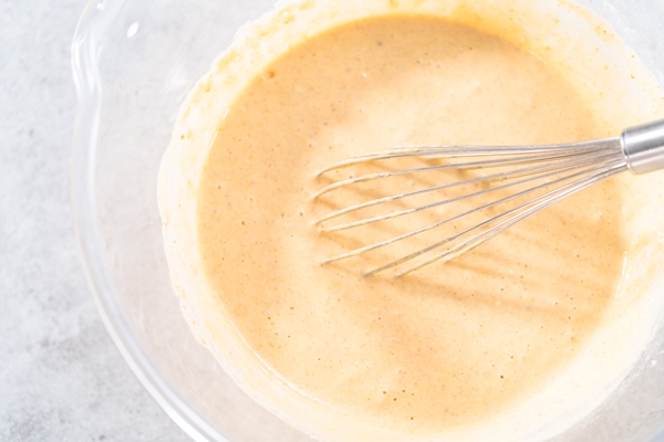 mixing ingredients in the glass mixing bowl to make pumpkin pancakes - Оладьи тыквенные