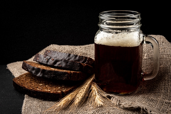 mug of kvass with rye bread on black background - Муромский квас