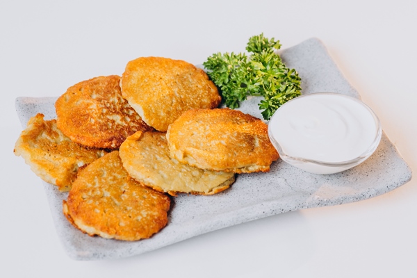 patato pancakes with sour cream isolated on wahite surface - Драники с чесноком