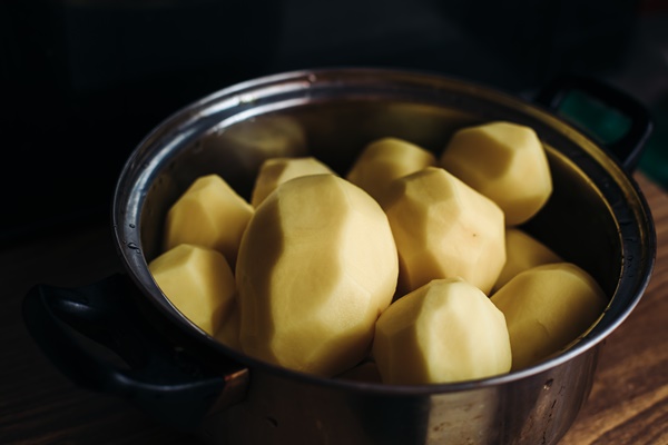 peeled potatoes in a silver pot clean potatoes for cooking dishes with peeled potatoes on a dark background drop of water - Постный суп картофельный с грибами