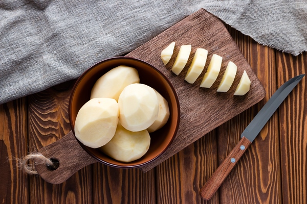 peeled sliced potatoes on a cutting board - Рагу из картофеля с красным сладким перцем и капустой