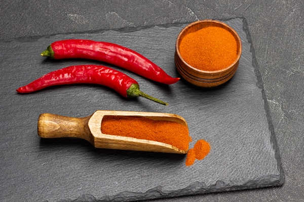 pods of fresh red pepper and ground paprika in scoop and in bowl on stone board - Подливка овощная постная
