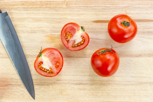 red tomatoes and slices on wooden cutting board - Рагу из картофеля с красным сладким перцем и капустой