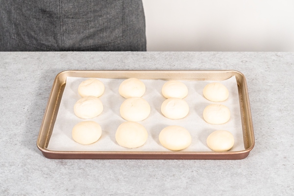 risen dinner rolls on a baking sheet lined with parchment paper before baking - Булки из несдобного дрожжевого теста