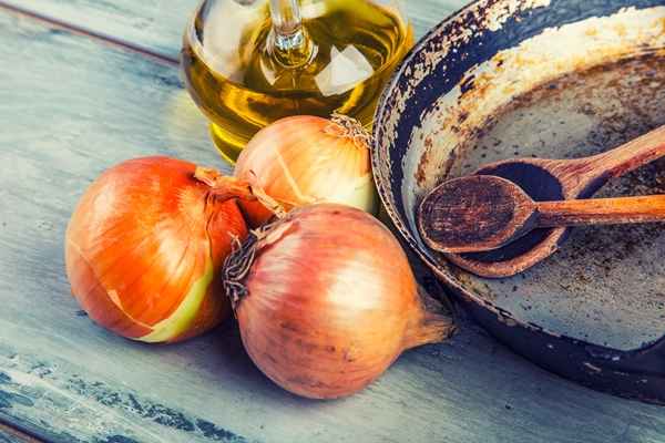 rustical concept consisting of an old pan with wooden spoons laying on a wooden table with onion and oil - Котлеты из картофеля и риса