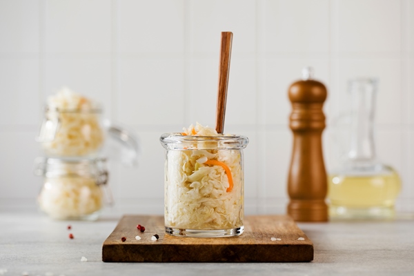 sauerkraut in a glass jar with a fork on a wooden board fermentation and canning of vegetables - Тушёная кислая капуста