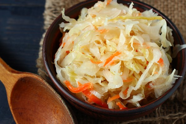 sauerkraut salad in a plate and a wooden spoon - Салат из квашеной капусты с чёрной редькой