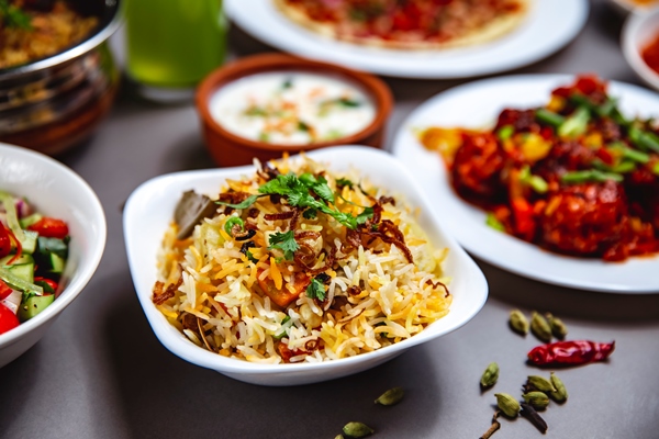 side view rice garnish with fried onion carrot greens and chili pepper on the table - Рис отварной