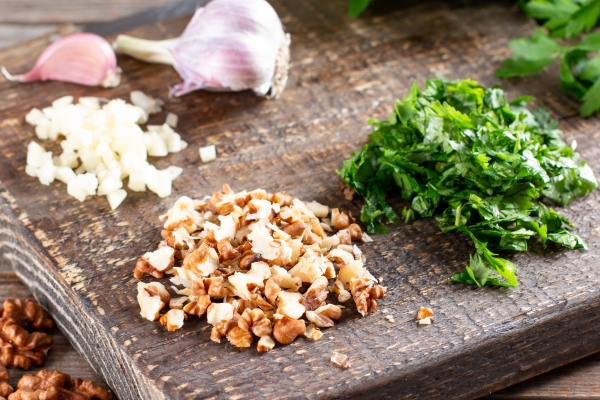 sliced walnuts herbs and garlic on a cutting board on a wooden table ingredients for a georgian dish healthy food - Баклажаны с грецкими орехами, постный стол