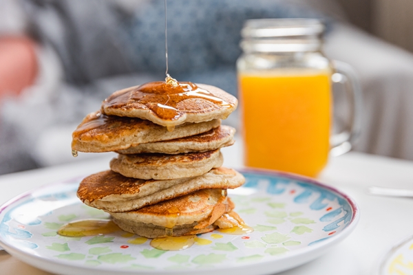 stack of pancakes with dripping maple syrup and a glass of fresh orange juice - Овсяные блины с ягодами и фруктами