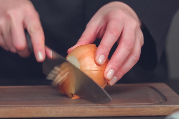 step by step dicing yellow onion on a wood cutting board - Салат с луком и кукурузой
