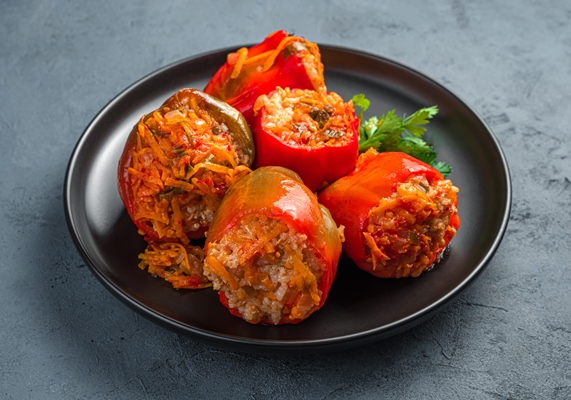 stuffed stewed bell peppers on a black plate on a dark background - Перец, фаршированный овощами