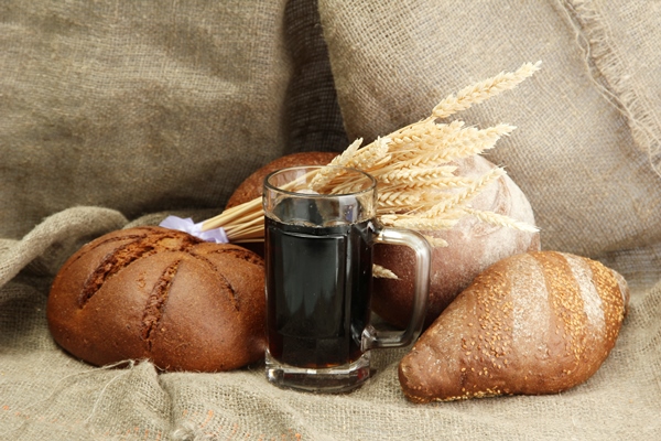 tankard of kvass and rye breads with ears on burlap background - Квас из сухого хлебного кваса
