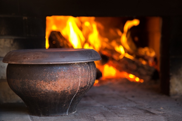the fire in the old traditional russian village oven in a rustic style pot of soup near the burning wood - Паренки из моркови с изюмом