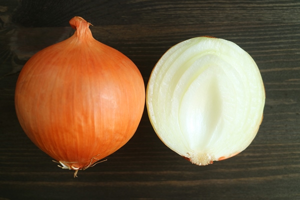 the unpeeled with cut in half onions isolated on dark color wooden background - Салат из моркови и капусты