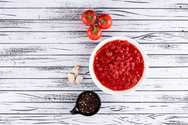 tomatoes and tomato sauce in white bowl black pepper powder in black bowl on white wooden surface - Постные фаршированные сладкие перцы