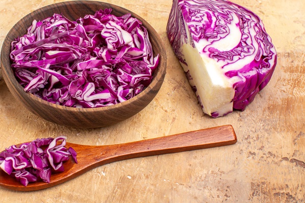 top view a bowl of chopped red cabbage and several red onions for vegetable salad on a wooden background with copy place - Салат из краснокочанной капусты с яблоками