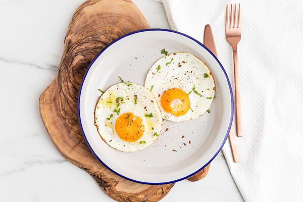 top view of breakfast fried eggs on plate with cutlery - Бутерброд с беконом и яйцом