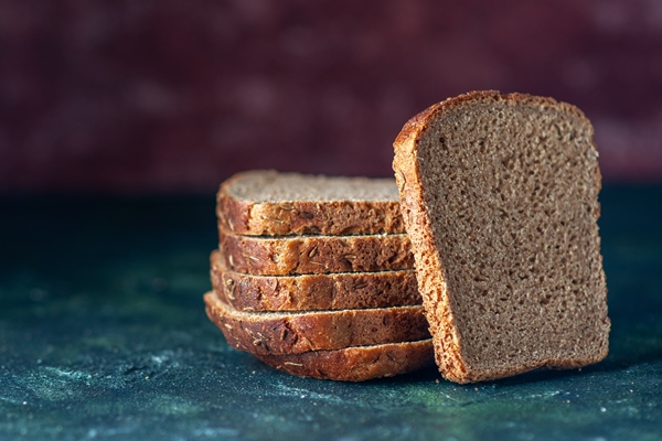 top view of dietary black bread slices on the left side on mixed colors background with free space - Бутерброд с бужениной и огурцом