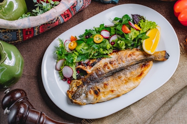 top view of roasted fish served with fresh vegetables and lemon on a plate - Окуни жареные, постный стол