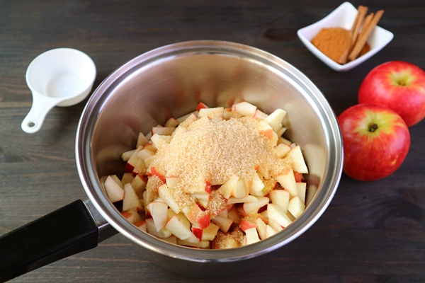 unrefined sugar added into the pot of diced apples for making apple compote - Маседуан из смеси свежих плодов