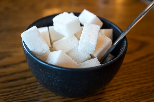 white sand sugar in wooden bowl and wooden spoon and cube sugar on wood table - Напиток клюквенный с мёдом