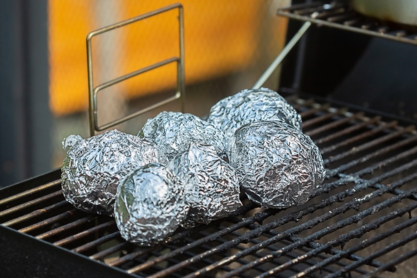 whole potatoes in foil are baked on charcoal grill - Картофель печёный