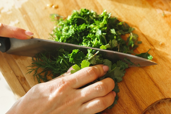 woman chopping green parsley and dill for healthy vegetarian salad - Салат с луком и кукурузой