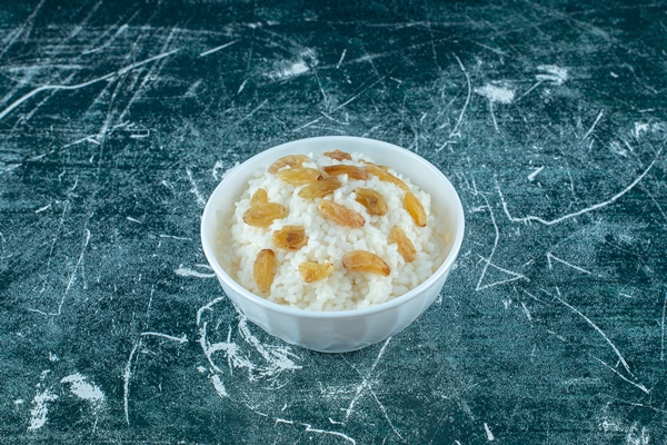a bowl of rice pudding with raisins on the blue background high quality photo - Поминальная кутия