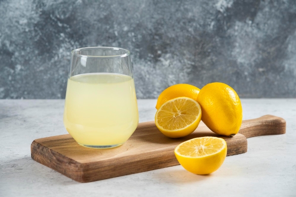 a glass cup of fresh lemon juice on a wooden board - Славский колач
