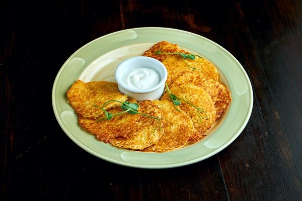 a traditional ukrainian dish potato pancakes with sour cream baked in the oven served in plate - Драники с овсяными хлопьями