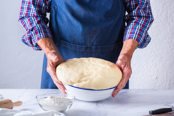baking eating at home healthy food and lifestyle concept senior baker man cooking kneading fresh dough with hands rolling with pin spreading the filling on the pie on a kitchen table with flour 1 - Гречневый хлеб в духовке
